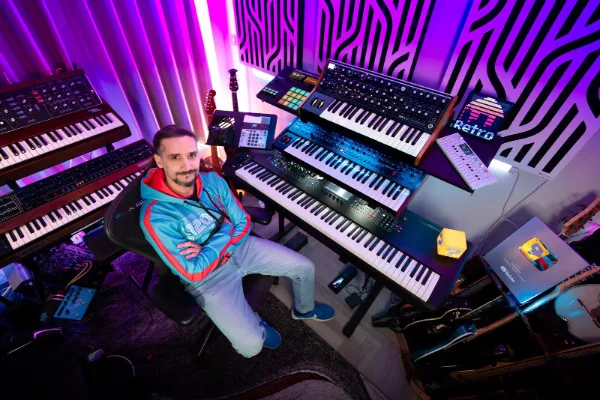 Mann sitzt in einem Studio mit vielen Keyboards